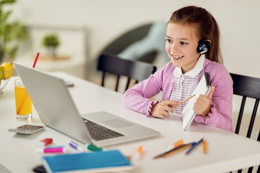 happy little girl having online class with teacher laptop (1)